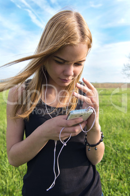 young blond woman listening to music with headphones outdoors