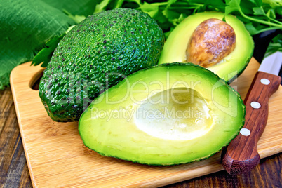 Avocado with knife on board