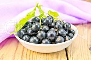 Black currants in bowl with napkin on board