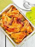 Chicken wings fried with vegetables in pan from foil