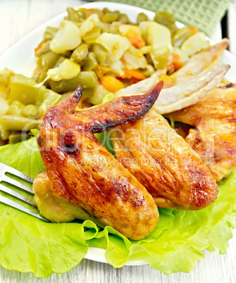 Chicken wings fried with vegetables in plate on board
