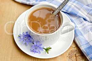 Chicory drink in white cup with spoon on board