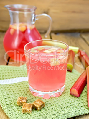 Compote from rhubarb in glassful and jug with sugar on board