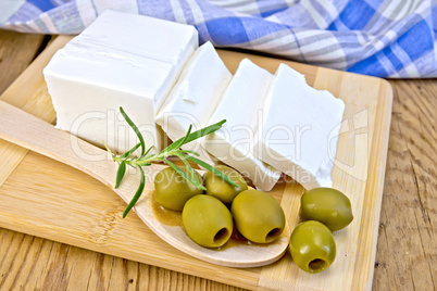 Feta with olives and rosemary in spoon on board