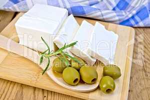 Feta with olives and rosemary in spoon on board