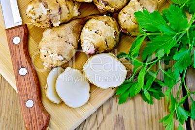 Jerusalem artichokes cut with knife and parsley on board