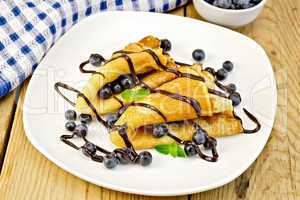 Pancakes with blueberries and chocolate on board