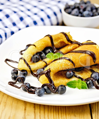 Pancakes with blueberries and chocolate on wooden board