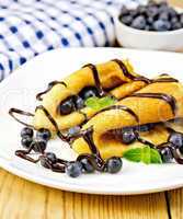 Pancakes with blueberries and chocolate on wooden board