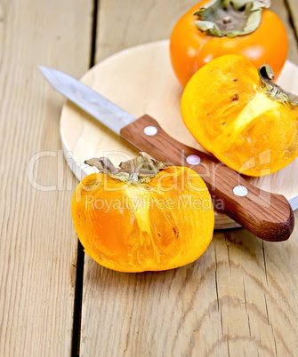 Persimmon with knife on wooden board