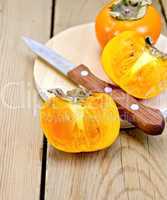 Persimmon with knife on wooden board