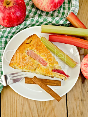 Pie with apple and rhubarb in plate on wooden board