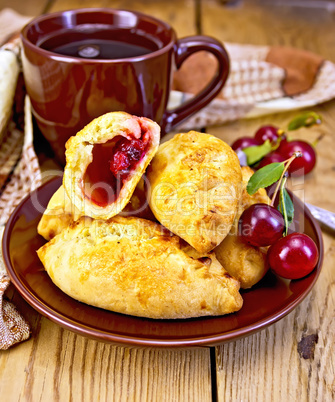 Pies with cherry and mug on board