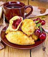Pies with cherry and mug on board