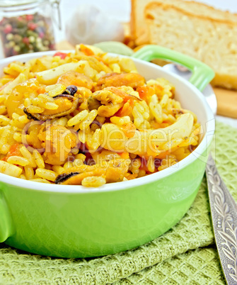 Pilaf with seafood in green pot on napkin