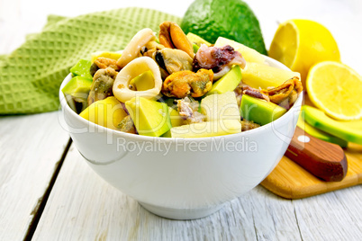 Salad seafood and avocado in bowl on light board