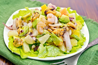 Salad seafood and fork on dark board