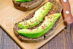 Sandwich with avocado and spices on board
