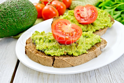 Sandwich with guacamole avocado and tomato on light board