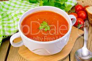 Soup tomato in bowl with spoon on board