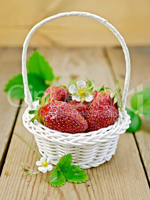 Strawberries in basket with flowers and leaves on board