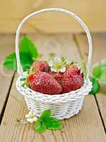 Strawberries in basket with flowers and leaves on board