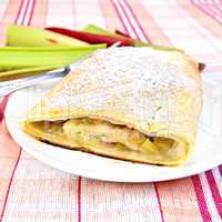 Strudel with rhubarb in plate on linen tablecloth