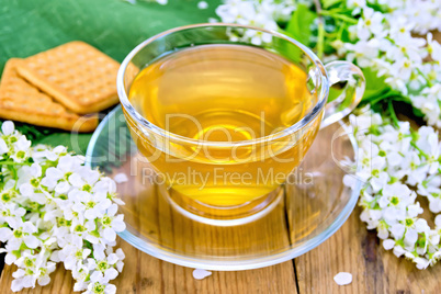 Tea in cup with cookies and flowers of bird cherry on board