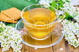 Tea in cup with cookies and flowers of bird cherry on board