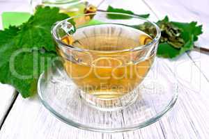 Tea with sage in cup on light board