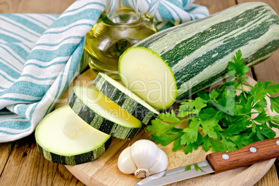 Zucchini green striped with garlic and oil on board