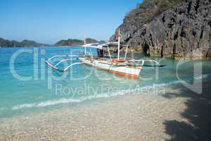 Boat anchored at rocky Coast and Turquoise Waters of Caramoan