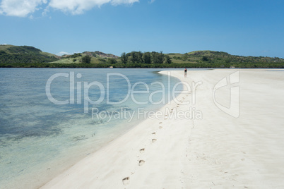 Lone Person Walking on Shore of White Sand Beach