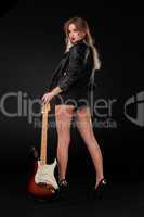 Beautiful young blonde dressed in black leather with electric guitar