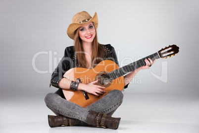 The beautiful girl in a cowboy's hat and acoustic guitar.