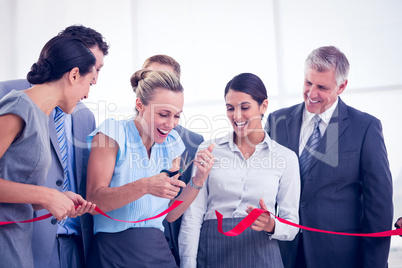 Happy business team cutting red ribbon