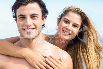 Happy couple in swimsuit looking at camera and embracing