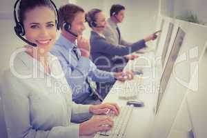 Business team working on computers and wearing headsets