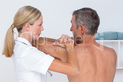 Doctor examining her patient shoulder