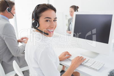 Business team working on computers and wearing headsets