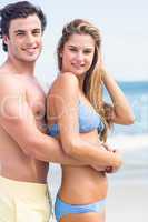 Happy couple in swimsuit looking at camera and embracing