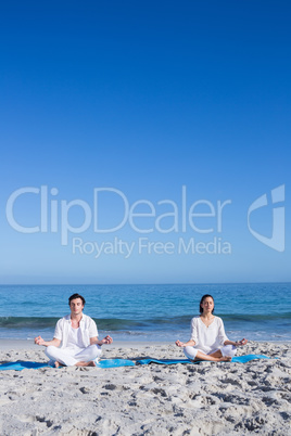 Happy couple doing yoga beside the water Happy couple doing yoga beside the water