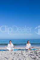 Happy couple doing yoga beside the water