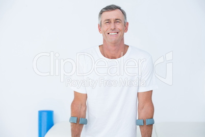 Patient standing with crutch looking at camera