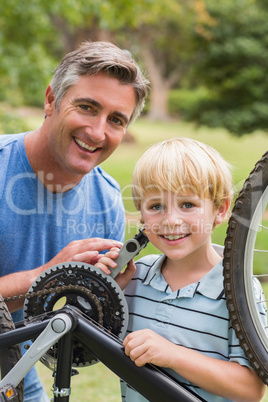 Happy father and his son fixing a bike