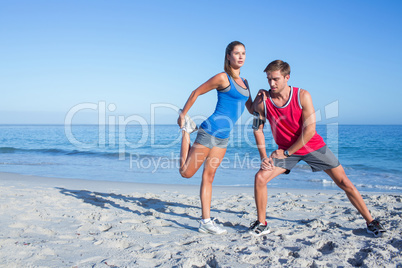 Happy couple stretching together beside the water