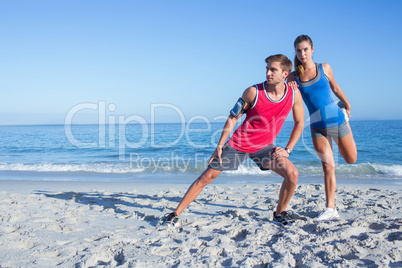 Happy couple stretching together beside the water