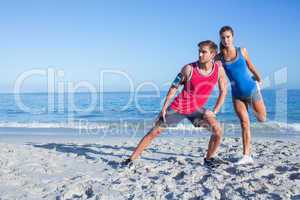 Happy couple stretching together beside the water