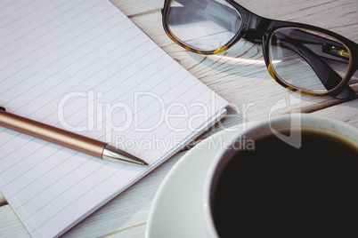 Empty notepad with reading glasses and cup of coffee