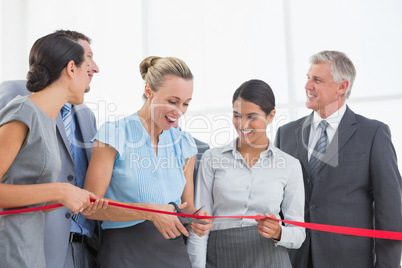 Happy business team cutting red ribbon Happy business team cutting red ribbon